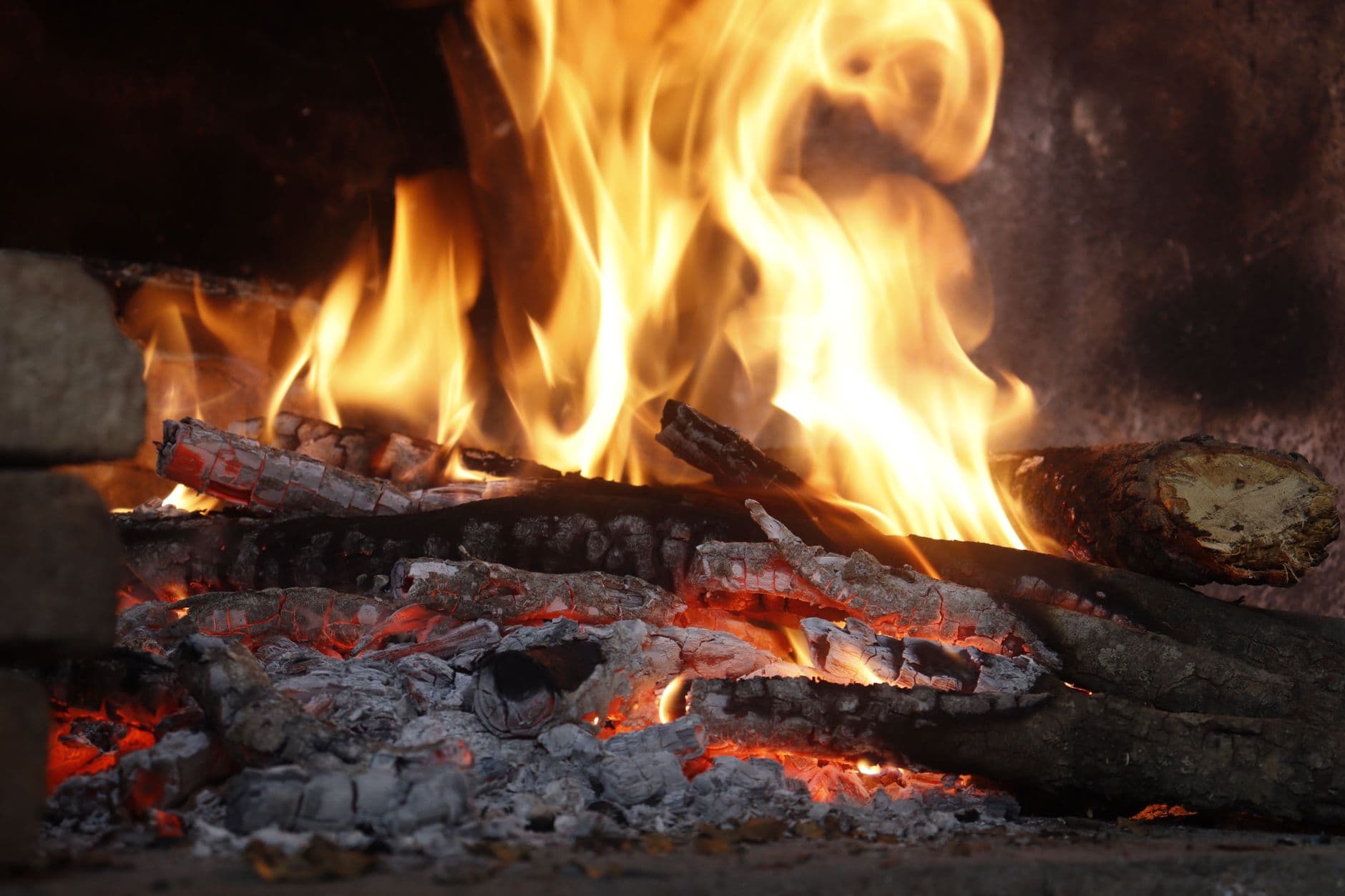 Close-up of a blazing fireplace with logs and glowing embers creating a warm atmosphere.